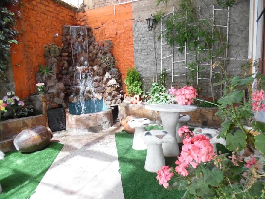 Jardín interior con cascada y mesas blancas
